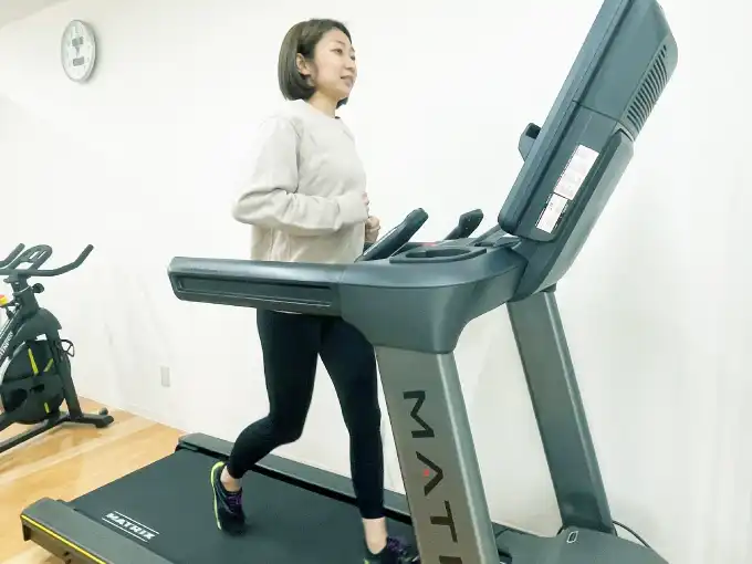 ランニングマシーンで走る女性