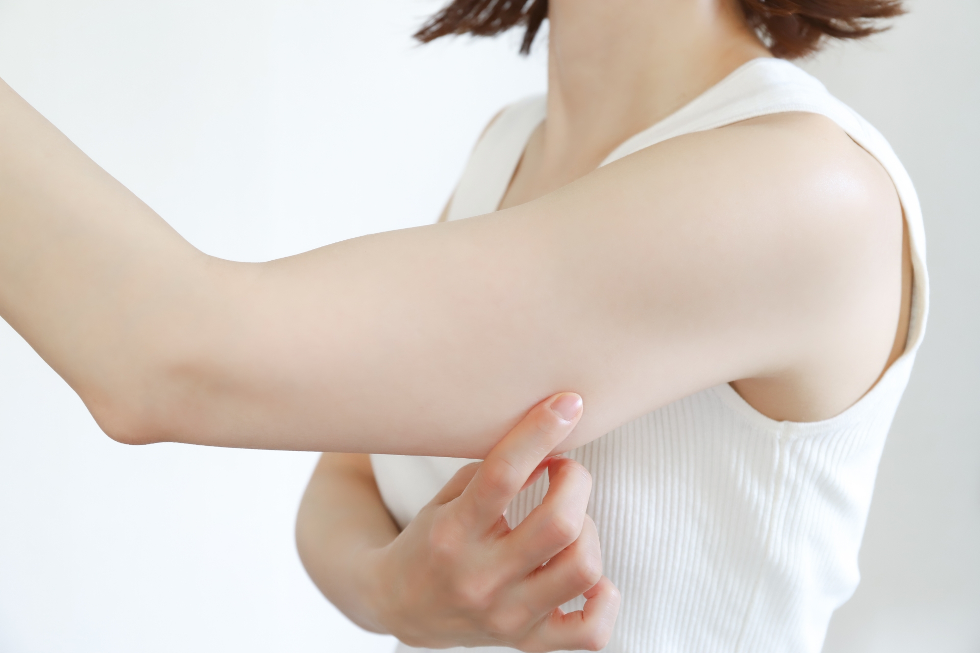 ダイエット成功後に気になる二の腕の皮膚のたるみをチェックする女性。急激な減量が肌に与える影響を解説